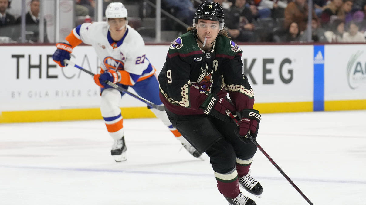 Sean Durzi of the Arizona Coyotes puts his arm around Logan Cooley