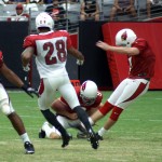 Kicker Chandler Catanzaro tries to get his field goal attempt pass a rushing Justin Bethel during Arizona Cardinals training camp Aug. 5. (Photo by Adam Green/Arizona Sports)