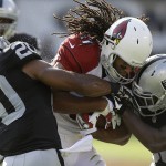 Arizona Cardinals wide receiver Larry Fitzgerald, center, is tackled by Oakland Raiders defensive back Nate Allen (20) and cornerback T.J. Carrie (38) during the first half of an NFL preseason football game in Oakland, Calif., Sunday, Aug. 30, 2015. (AP Photo/Ben Margot)