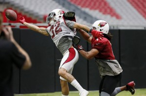 Arizona Cardinals' Tyrann Mathieu (32) reaches out for a pass intended for Larry Fitzgerald, right, during NFL football training camp Thursday, Aug. 13, 2015, in Glendale, Ariz. (AP Photo/Ross D. Franklin)