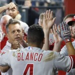 Philadelphia Phillies' Andres Blanco, foreground, is greeted in the dugout by teammates, including Darin Ruf, right, and conditioning coordinator Paul Fourafter, left, after hitting a home run against the Arizona Diamondbacks during the third inning of a baseball game Wednesday, Aug. 12, 2015, in Phoenix. (AP Photo/Ross D. Franklin)