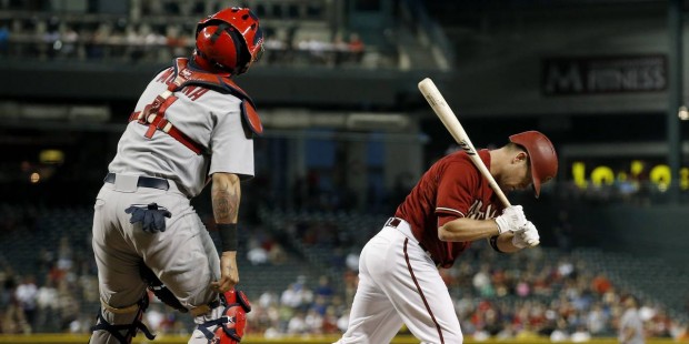 Arizona Diamondbacks' Aaron Hill, right, carries his bat as he runs down the line after flying out,...