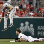 Arizona Diamondbacks shortstop Nick Ahmed comes down after jumping up in attempt to field the throw to second from the outfield, but Washington Nationals' Bryce Harper (34) was safe at second base with a double during the first inning of a baseball game at Nationals Park, Tuesday, Aug. 4, 2015, in Washington. (AP Photo/Alex Brandon)
