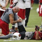 Arizona Cardinals' Larry Fitzgerald, right, gets stretched out by strength and conditioning coach Buddy Morris during NFL football training camp Thursday, Aug. 13, 2015, in Glendale, Ariz. (AP Photo/Ross D. Franklin)