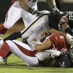 Arizona Cardinals quarterback Logan Thomas (6) is tackled Oakland Raiders defensive end Shelby Harris, bottom, and outside linebacker Neiron Ball (58) during the second half of an NFL preseason football game in Oakland, Calif., Sunday, Aug. 30, 2015. Ball was called for a face mask penalty on the play. (AP Photo/Ben Margot)