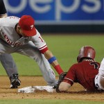 Philadelphia Phillies' Cesar Hernandez, left, applies a tag to Arizona Diamondbacks' Aaron Hill, right, during the fifth inning of a baseball game Wednesday, Aug. 12, 2015, in Phoenix. Originally called safe, Hill was ruled out after a challenge by the Phillies. (AP Photo/Ross D. Franklin)