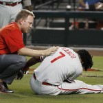 Philadelphia Phillies assistant athletic trainer Shawn Fcasni, left, attends to Maikel Franco (7) after Franco was hit by a pitch thrown by Arizona Diamondbacks' Jeremy Hellickson during the first inning of a baseball game Tuesday, Aug. 11, 2015, in Phoenix.  Franco left the game. (AP Photo/Ross D. Franklin)