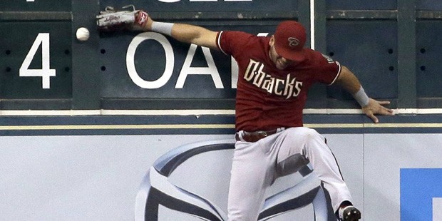 Arizona Diamondbacks left fielder David Peralta hits the wall while trying to catch a double hit by...