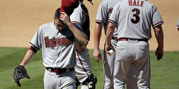 Arizona Diamondbacks starting pitcher Patrick Corbin, left, wipes his face as he leaves the game af...