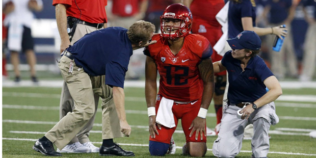 Arizona quarterback Anu Solomon (12) is checked by trainers during the first half of an NCAA colleg...