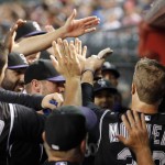 Colorado Rockies' Justin Morneau, right, celebrates his run scored against the Arizona Diamondbacks with teammates in the dugout during the second inning of a baseball game Wednesday, Sept. 30, 2015, in Phoenix. (AP Photo/Ross D. Franklin)