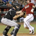 Arizona Diamondbacks' Paul Goldschmidt, right, drops into his slide to score a run as Colorado Rockies' Dustin Garneau, left, waits for a late throw to home plate during the sixth inning of a baseball game Wednesday, Sept. 30, 2015, in Phoenix. (AP Photo/Ross D. Franklin)