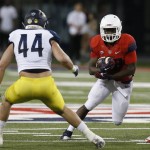 Arizona running back Nick Wilson carries for a first down in front of Northern Arizona linebacker Jake Thomas (44) during the first half of an NCAA college football game, Saturday, Sept. 19, 2015, in Tucson, Ariz. (AP Photo/Rick Scuteri)