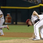 Arizona Diamondbacks' Chase Anderson, right, wipes the dirt on the mound after giving up a home run to San Francisco Giants' Tim Hudson, left, during the third inning of a baseball game Tuesday, Sept. 8, 2015, in Phoenix.  Hudson's home run was the second back-to-back homer after Giants' Gregor Blanco. (AP Photo/Ross D. Franklin)