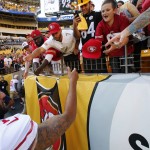 San Francisco 49ers quarterback Colin Kaepernick, left, hands his cap to a young fan as he walks off the field after an NFL football game against the Pittsburgh Steelers at Heinz Field in Pittsburgh, Sunday, Sept. 20, 2015. The Steelers won 43-18. (AP Photo/Gene J. Puskar)
