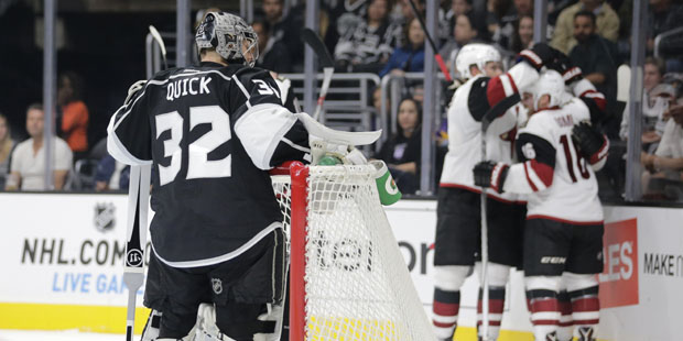 Los Angeles Kings goalie Jonathan Quick, left, grabs a drink as the Arizona Coyotes players celebra...
