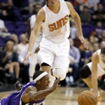 Sacramento Kings' Rajon Rondo, left, passes the ball as he falls down as Phoenix Suns' Devin Booker, right, arrives to defend during the first half of an NBA preseason basketball game Wednesday, Oct. 7, 2015, in Phoenix. (AP Photo/Ross D. Franklin)
