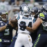 Seattle Seahawks quarterback Russell Wilson, left, tries to break up a scuffle involving Carolina Panthers' Josh Norman and several Seahawks players in the first half of an NFL football game, Sunday, Oct. 18, 2015, in Seattle. (AP Photo/Stephen Brashear)