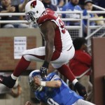 Arizona Cardinals defensive end Cory Redding (90) jumps over Detroit Lions quarterback Matthew Stafford (9) after intercepting a pass during the first half of an NFL football game, Sunday, Oct. 11, 2015, in Detroit. (AP Photo/Duane Burleson)
