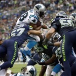 Carolina Panthers running back Jonathan Stewart, top, leaps over Seattle Seahawks outside linebacker Mike Morgan (57) to score a touchdown in the second half of an NFL football game, Sunday, Oct. 18, 2015, in Seattle. (AP Photo/Elaine Thompson)
