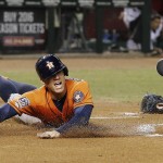 Houston Astros' George Springer, left, dives around Arizona Diamondbacks' Welington Castillo, right, to score a run during the first inning of a baseball game Friday, Oct. 2, 2015, in Phoenix. (AP Photo/Ross D. Franklin)