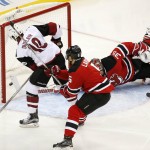 Arizona Coyotes left wing Anthony Duclair (10) scores a goal on New Jersey Devils goalie Cory Schneider (35) as defenseman Adam Larsson (5), of Sweden, defends during the third period of an NHL hockey game, Tuesday, Oct. 20, 2015, in Newark, N.J. The Devils won 3-2 in overtime. (AP Photo/Julio Cortez)
