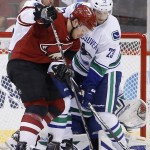 Arizona Coyotes' Max Domi, front, tries to get control of the puck as Vancouver Canucks' Alexander Edler (23), of Sweden, and Yannick Weber, back left, of Switzerland, defend during the first period of an NHL hockey game Friday, Oct. 30, 2015, in Glendale, Ariz. (AP Photo/Ross D. Franklin)