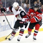 Arizona Coyotes center Brad Richardson (12) and New Jersey Devils defenseman Damon Severson (28) compete for the puck during the first period of an NHL hockey game, Tuesday, Oct. 20, 2015, in Newark, N.J. (AP Photo/Julio Cortez)