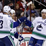 Vancouver Canucks' Daniel Sedin, back left, of Sweden, celebrates his goal against the Arizona Coyotes with Alexander Edler (23), of Sweden, and Henrik Sedin (33), of Sweden, during the second period of an NHL hockey game Friday, Oct. 30, 2015, in Glendale, Ariz. (AP Photo/Ross D. Franklin)