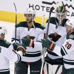Minnesota Wild's Jason Zucker (16), Marco Scandella (6) and Ryan Suter (20) celebrate with goalie Devan Dubnyk after an NHL hockey game win against the Arizona Coyotes on Thursday, Oct. 15, 2015, in Glendale, Ariz.  The Wild defeated the Coyotes 4-3. (AP Photo/Ross D. Franklin)
