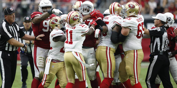 The San Francisco 49ers and the Arizona Cardinals are separated by the referees during the first ha...