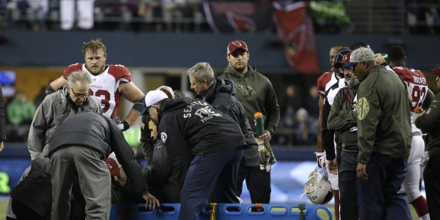 A backboard is brought in to take injured Arizona Cardinals guard Mike Iupati off the field, during...
