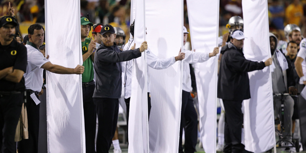Oregon football team staff use sheets to block the view of signal callers on the team bench not all...