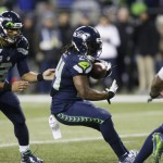 Seattle Seahawks quarterback Russell Wilson, left, hands off to running back Marshawn Lynch, center, on a touchdown run against the Arizona Cardinals during the second half of an NFL football game, Sunday, Nov. 15, 2015, in Seattle. (AP Photo/Stephen Brashear)