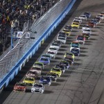 Pole-sitter Jimmie Johnson, front right, and Kurt Busch, front left, lead the field past the start-finish line to start the NASCAR Sprint Cup series auto race at Phoenix International Raceway, Sunday, Nov. 15, 2015, in Avondale, Ariz. (AP Photo/Ralph Freso)