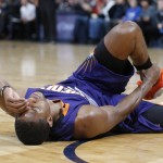 Phoenix Suns guard Brandon Knight reaches for his ankle after being injured while driving the lane for a shot against the Denver Nuggets in the first half of an NBA basketball game Friday, Nov. 20, 2015, in Denver. Knight headed to the locker room after the play. (AP Photo/David Zalubowski)