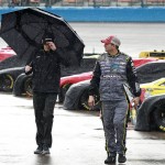 Crew members for driver Paul Menard walk down pit road in the rain before the NASCAR Sprint Cup Series auto race at Phoenix International Raceway, Sunday, Nov. 15, 2015, in Avondale, Ariz. The race start was delayed. (AP Photo/Ralph Freso)