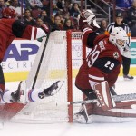 Arizona Coyotes' Anders Lindback (29), of Sweden, makes a save on a shot by New York Rangers' Jarret Stoll, bottom left, as he gets clobbered by Coyotes' Michael Stone, top left, during the second period of an NHL hockey game, Saturday, Nov. 7, 2015, in Glendale, Ariz. (AP Photo/Ross D. Franklin)