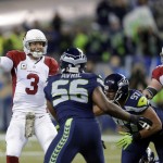 Arizona Cardinals quarterback Carson Palmer (3) passes under pressure from Seattle Seahawks defensive end Cliff Avril (56) during the first half of an NFL football game, Sunday, Nov. 15, 2015, in Seattle. (AP Photo/Stephen Brashear)