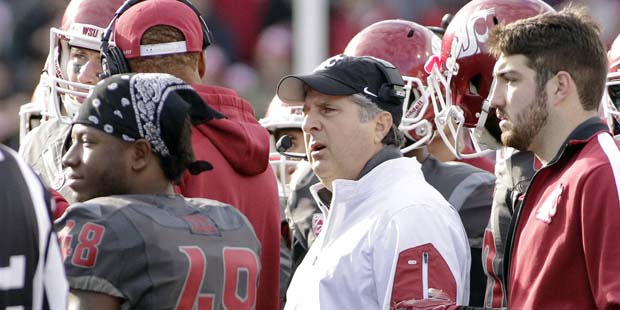Washington State head coach Mike Leach, center, speaks in the huddle during a timeout in the first ...