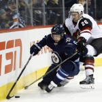 Winnipeg Jets' Alex Burmistrov (6) and Arizona Coyotes' Michael Stone (26) dig for the puck during the second period of an NHL hockey game, in Winnipeg, Manitoba on Saturday, Nov. 21, 2015. (John Woods/The Canadian Press via AP) MANDATORY CREDIT