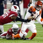 Cincinnati Bengals quarterback Andy Dalton (14) is tackled by Arizona Cardinals defensive end Frostee Rucker (92) and linnebacker Kevin Minter (51) during the first half of an NFL  football game, Sunday, Nov. 22, 2015, in Glendale, Ariz. (AP Photo/Rick Scuteri)