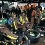 Pit crew members of Kyle Busch sit on their Goodyear racing tires as they wait out a rain delay before the NASCAR Sprint Cup Series auto race at Phoenix International Raceway, Sunday, Nov. 15, 2015, in Avondale, Ariz. (AP Photo/Ralph Freso)