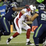 Arizona Cardinals quarterback Carson Palmer, center is hit by Seattle Seahawks defensive end Cliff Avril, left, before fumbling during the second half of an NFL football game, Sunday, Nov. 15, 2015, in Seattle. The Seahawks recovered and scored a touchdown on the following play. (AP Photo/Elaine Thompson)