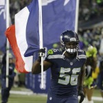 Seattle Seahawks defensive end Cliff Avril runs out of the tunnel carrying a French flag in support of France, which was hit with terrorist attacks in Paris on Friday, before an NFL football game against the Arizona Cardinals, Sunday, Nov. 15, 2015, in Seattle. (AP Photo/Elaine Thompson)