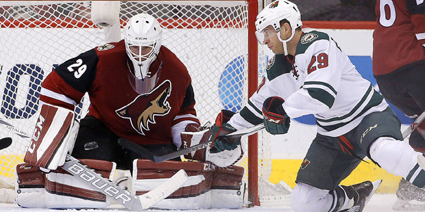 Arizona Coyotes' Anders Lindback, left, of Sweden, makes a save on a shot as Minnesota Wild's Jason...