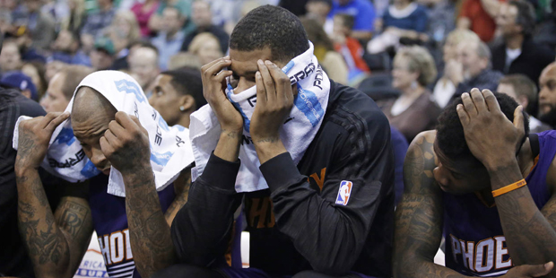 Phoenix Suns' P.J. Tucker, Markieff Morris and Eric Bledsoe, from left, sit on the bench late in th...