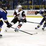 Arizona Coyotes' Klas Dahlbeck passes a puck between St. Louis Blues' Carl Gunnarsson, left, and Troy Brouwer, right, during the first period of an NHL hockey game Tuesday, Dec. 8, 2015, in St. Louis. (AP Photo/Jeff Roberson)
