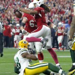 Arizona Cardinals wide receiver Larry Fitzgerald (11) celebrates after making a touchdown catch as Green Bay Packers linebacker Joe Thomas (48) sits on the turf during the first half of an NFL football game, Sunday, Dec. 27, 2015, in Glendale, Ariz. (AP Photo/Ross D. Franklin)