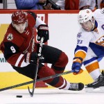 Arizona Coyotes' Viktor Tikhonov (9), of Russia, gets tripped up as he loses control of the puck in front of New York Islanders' John Tavares (91) during the second period of an NHL hockey game Saturday, Dec. 19, 2015, in Glendale, Ariz. (AP Photo/Ross D. Franklin)